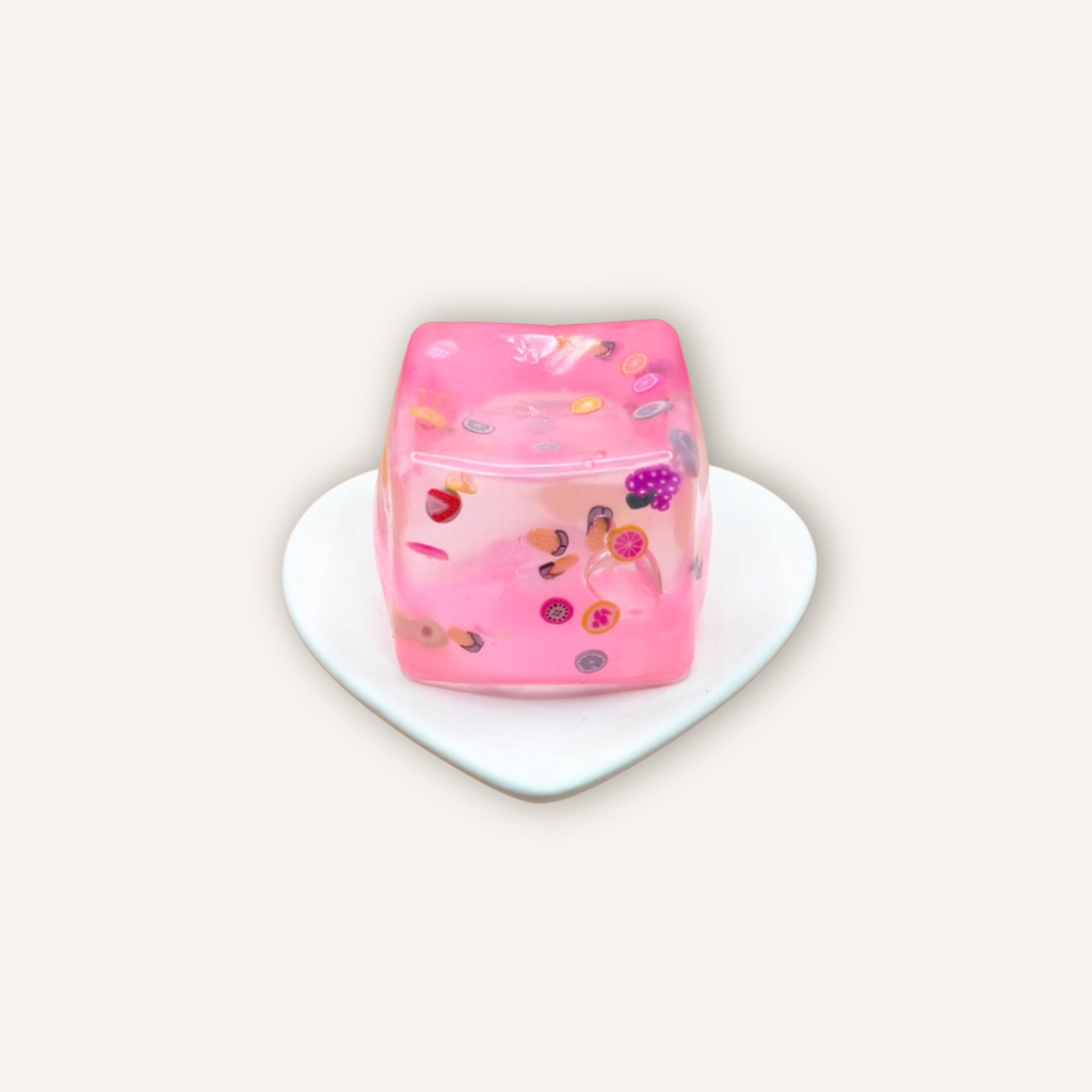 Pink fruit filled squishy cube sensory toy with colourful fruit pieces and a soft gel-filled texture for satisfying squeezing and fidgeting.
